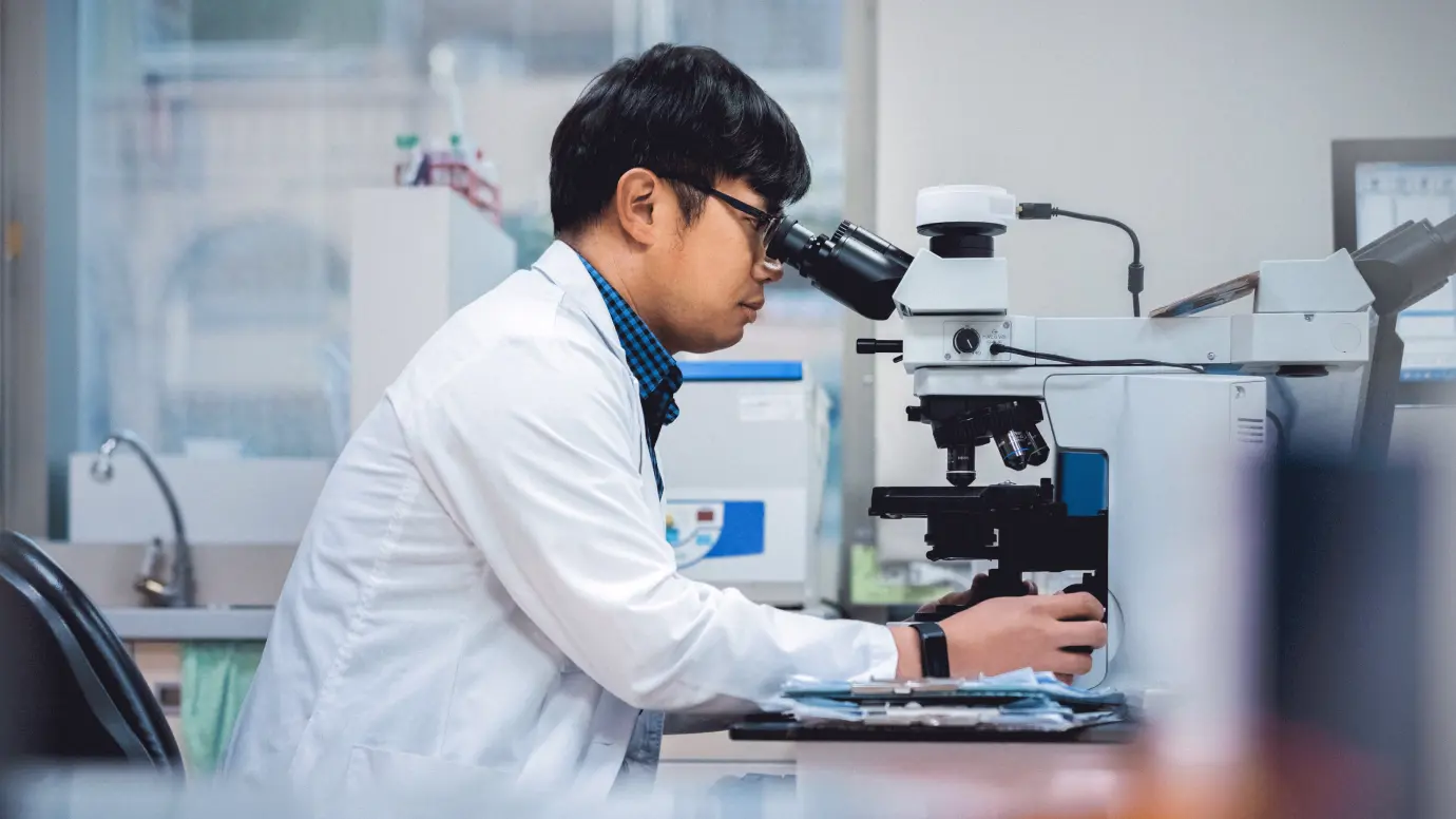 Researcher works with microscope to develop new treatments for IgA nephritis